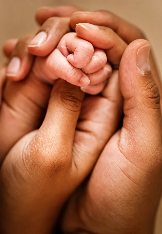 Newborn hand holding a parent's finger
