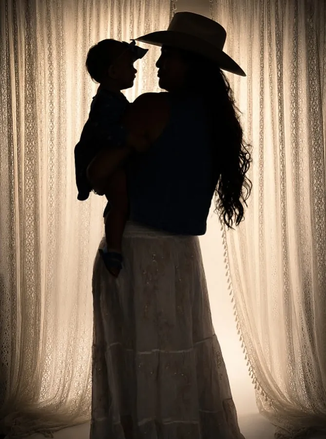 Mother and toddler silhouetted against a lace curtain