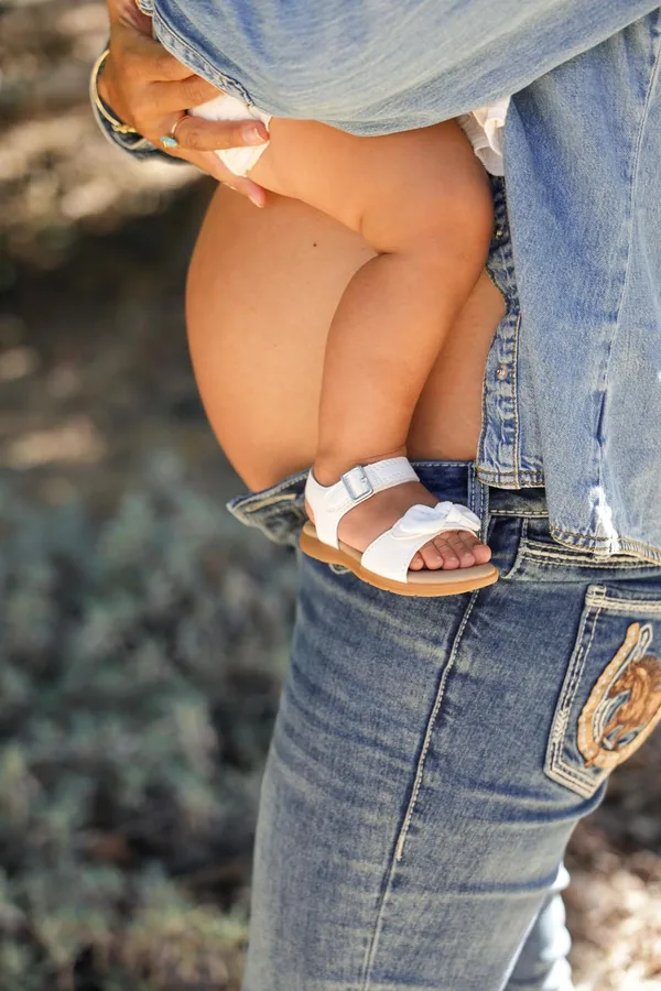 Baby's sandals tucked against her mother at golden hour