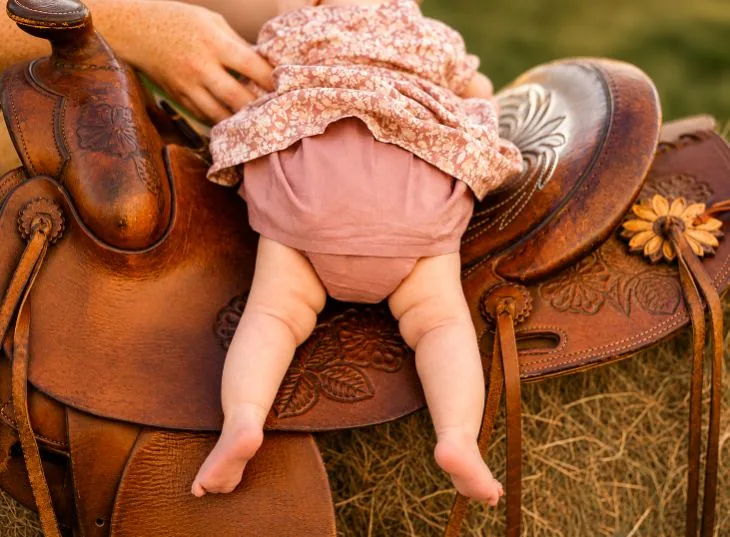 Baby resting on a tooled leather saddle at golden hour