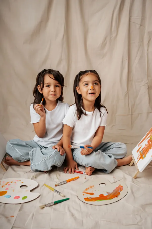 Two sisters with paint brushes and palettes during a studio session