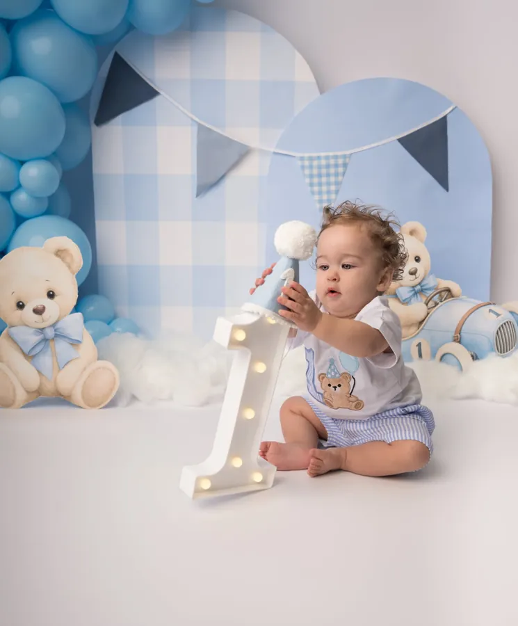 One year old holding a light-up number one at his teddy bear birthday session